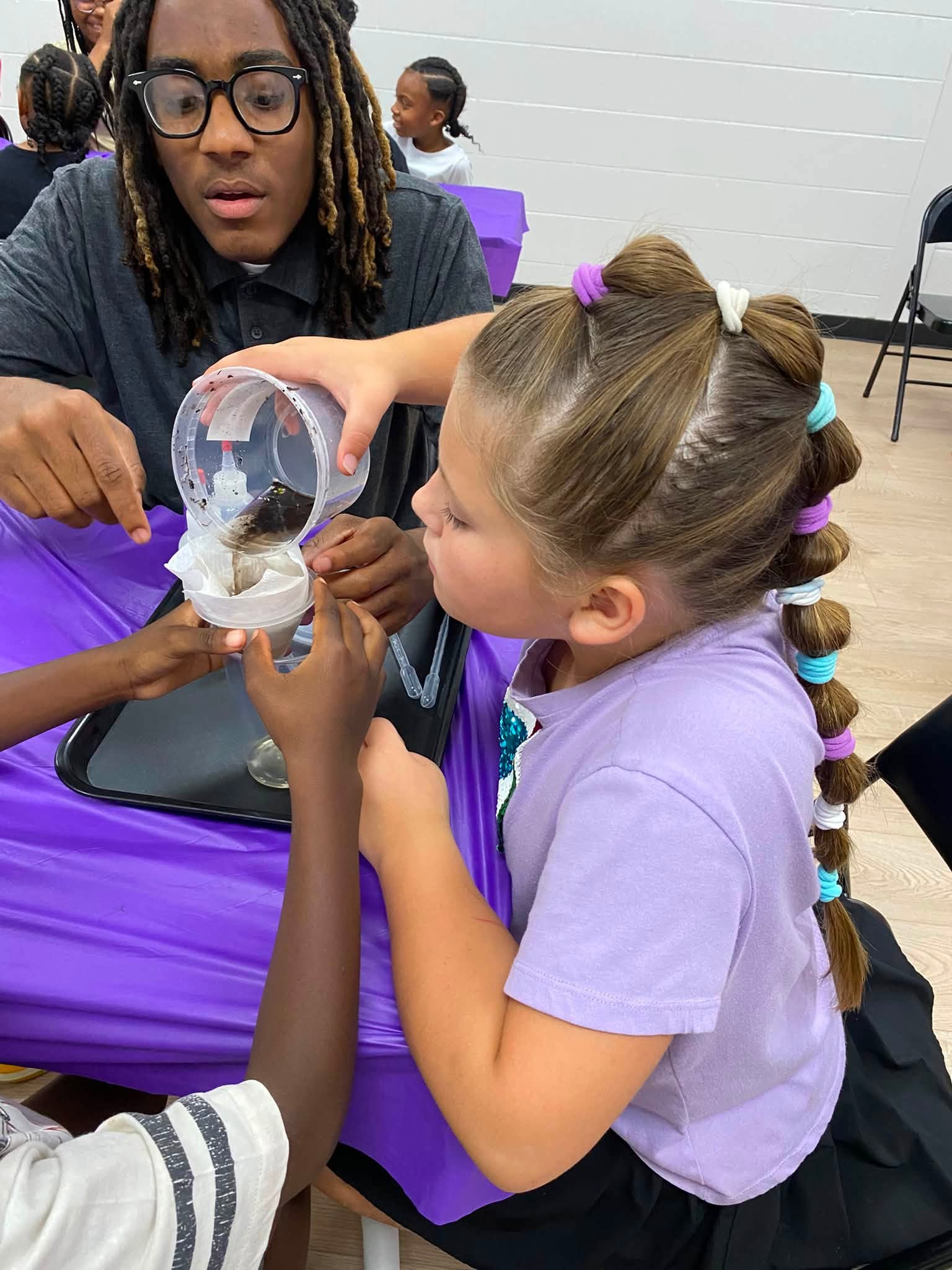A man helping a girl do a science experiment with liquid.